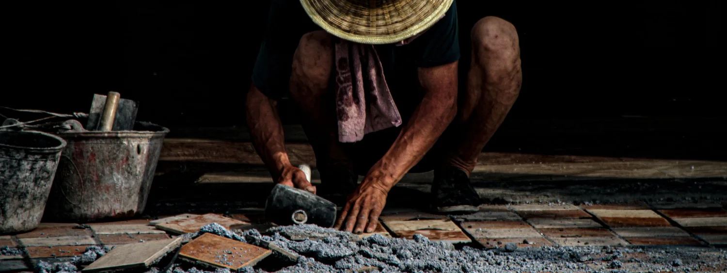 Montator care așază plăci ceramice, cu unelte și mortar în apropiere