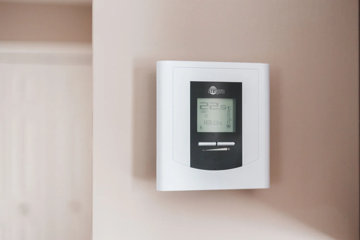 Termostat digital alb montat pe peretele unei locuințe