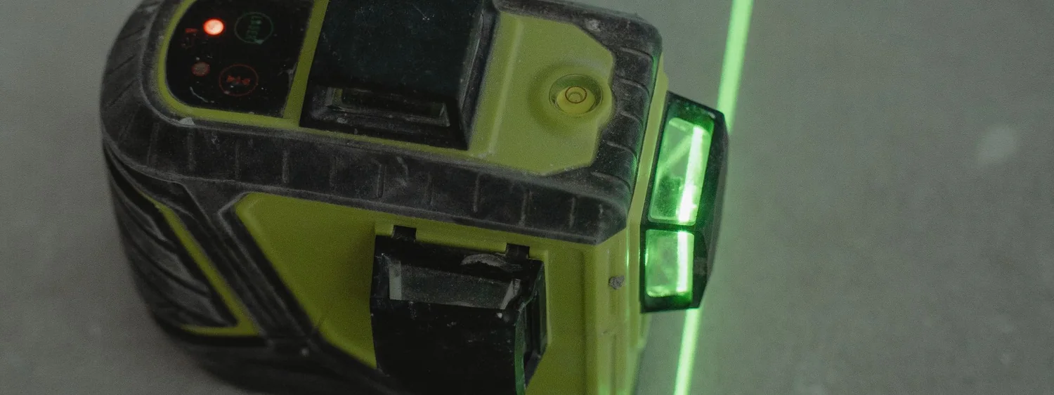 Nivelă laser cu fascicul verde pe un suport de beton