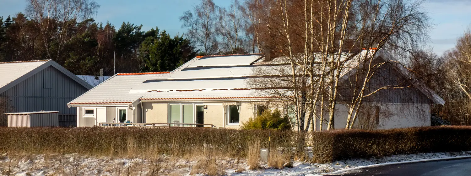 Casă cu panouri fotovoltaice acoperite de zăpadă pe acoperiș