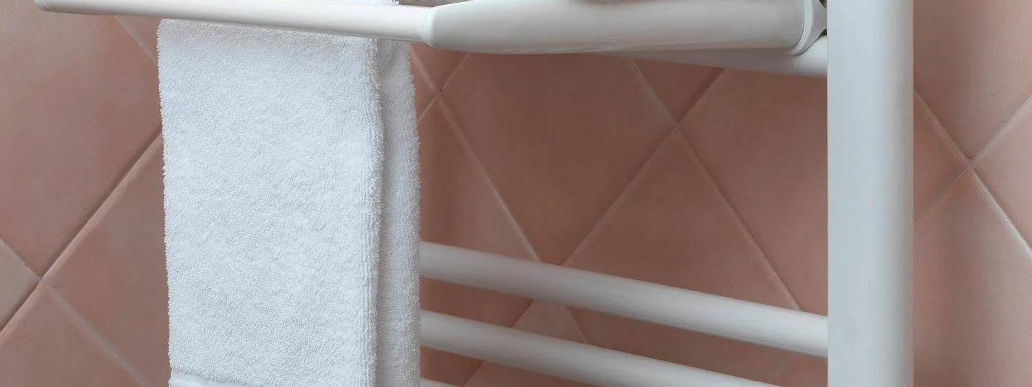 Radiator portprosop alb cu suport și prosoape într-o baie